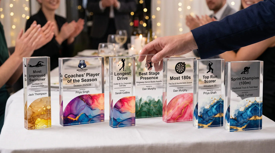 Person organizing custom acrylic sports trophies with colorful resin bases displayed on a banquet table during an awards ceremony.