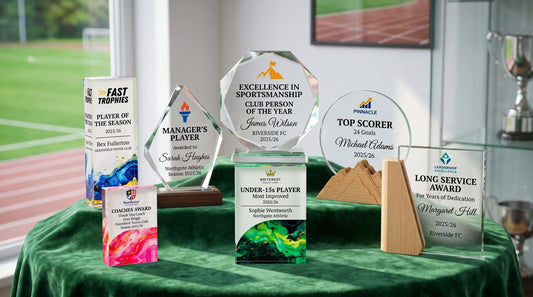 Custom crystal-style sports trophies with personalised club logos and award text displayed for a UK sports club presentation night.