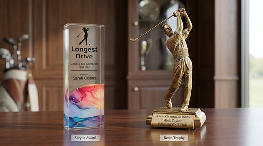 Personalised golf trophy comparison showing a clear acrylic Longest Drive award beside a gold resin Club Champion golfer trophy.