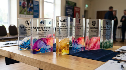 Fast Trophies UK custom acrylic and crystal sports awards featuring colorful resin bases arranged on a wooden presentation table.