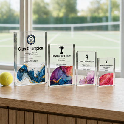 Four tennis trophies in different sizes set out for a club finals day prize-giving